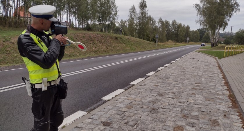Zdjęcie: Policjant ruchu drogowego stojąc na skraju drogi dokonuje pomiaru prędkości / fot: KPP Szczecinek